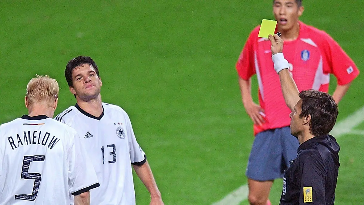 Der-Schweizer-Schiedsrichter-Urs-Meier-r-vorn-zeigt-dem-deutschen-Mittelfeldspieler-Michael-Ballack-2-v-l-die-Gelbe-Karte-An-Ballacks-Seite-Carsten-Ramelow-l-Die-deutsche-Fussballnationalmannschaft-gewinnt-am-25-06-2002-in-Seoul-das-Halbfinalspiel-des-17-WM-Turniers-gegen-die-Elf-des-Gastgebers-Suedkorea-durch-Ballacks-Tor-mit-1-0-und-qualifiziert-sich-damit-zum-siebentenmal-fuer-das-Endspiel-in-dem-Ballack-nach-seiner-zweiten-Gelben-Karte-fehlt