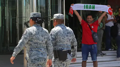 Members-of-the-National-Guard-patrol-outside-the-hotel-where-Iran-s-national-football-team-is-staying-as-a-fan-holds-up-a-scarf-while-waiting-for-the-players-to-depart-for-a-training-session-at-Estadio-Caliente-ahead-of-the-2026-FIFA-World-Cup-in-Tijuana-Mexico-June-9-2026