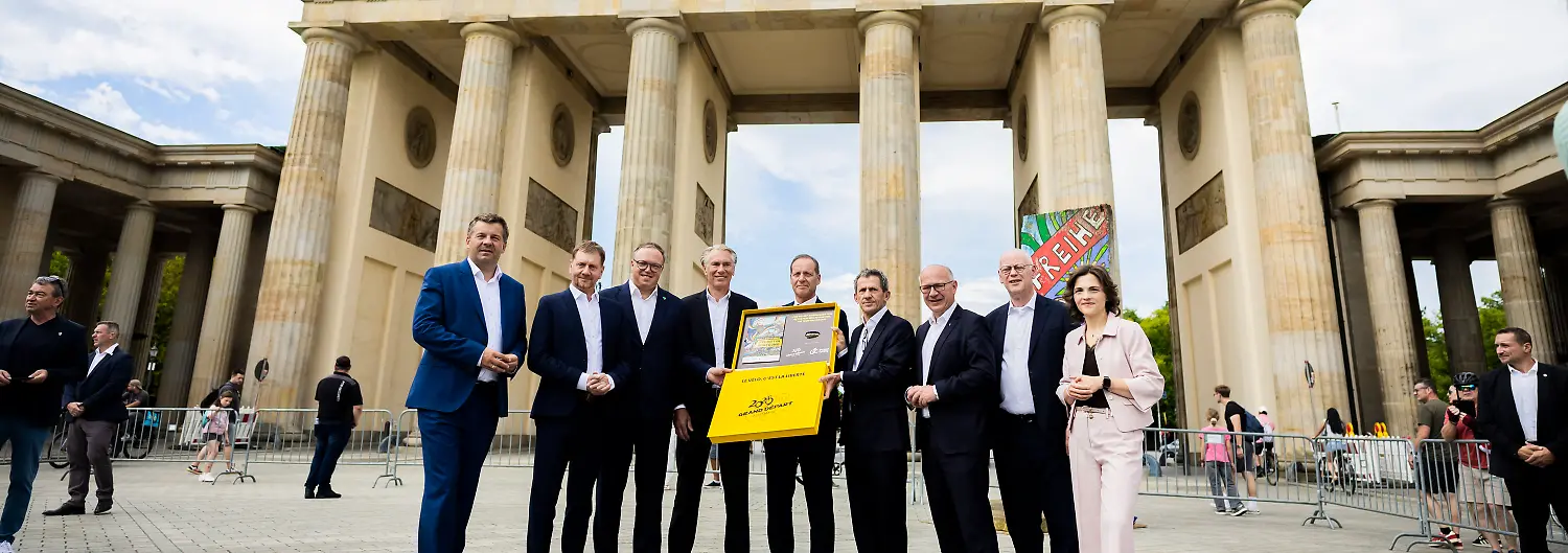 29-07-2026-Berlin-Radsport-Sven-Schulze-CDU-l-r-Ministerpraesident-von-Sachsen-Anhalt-Michael-Kretschmer-CDU-Ministerpraesident-von-Sachsen-Mario-Voigt-CDU-Ministerpraesident-von-Thueringen-Bernd-Dankowski-Praesident-des-deutschen-Radsportverbandes-German-Cycling-Christian-Prudhomme-Direktor-der-Tour-de-France-Yann-Le-Moenner-Geschaeftsfuehrer-A-S-O-Germany-Kai-Wegner-CDU-Regierender-Buergermeister-von-Berlin-Rudolf-Scharping-und-Elisabeth-Kaiser-Staatsministerin-und-Beauftragte-der-Bundesregierung-fuer-Ostdeutschland-stehen-bei-einem-Bildtermin-zur-Uebergabe-der-Bewerbung-um-den-Start-der-Tour-de-France-2029-in-Mitteldeutschland-an-den-Tourchef-Prudhomme-vor-dem-Brandenburger-Tor