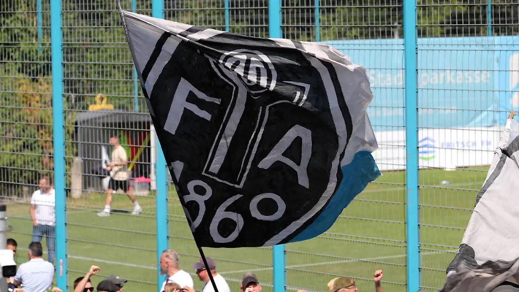 Fussball-Herren-Regionalliga-regional-league-Bayern-Saison-2026-2027-TSV-Munich-1860-Training-Fanmarsch-Auflauf-der-Ultras-EV-Anh-nger-am-Trainingsgel-nde-bei-Training-des-TSV-Munich-1860-Ges-nge-Anfeuern-Fahne-mit-dem-Logo-der-Fussballabteilung