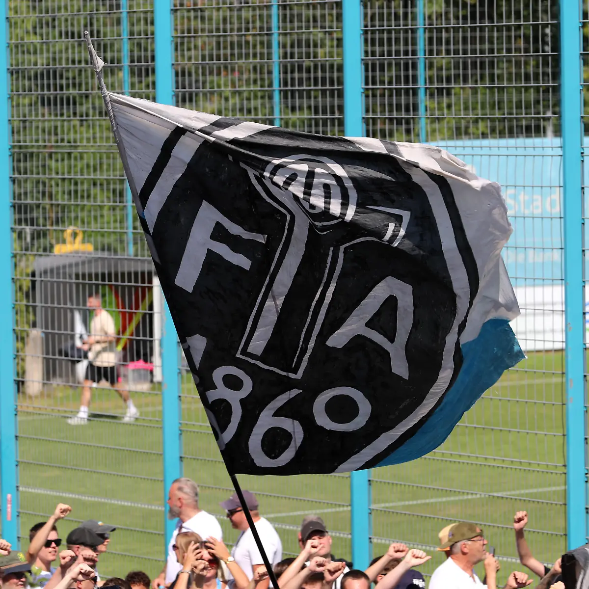 Fussball-Herren-Regionalliga-regional-league-Bayern-Saison-2026-2027-TSV-Munich-1860-Training-Fanmarsch-Auflauf-der-Ultras-EV-Anh-nger-am-Trainingsgel-nde-bei-Training-des-TSV-Munich-1860-Ges-nge-Anfeuern-Fahne-mit-dem-Logo-der-Fussballabteilung